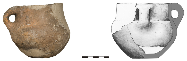 Kubek typu K22, niezdobiony. Krawędź zaokrąglona, dno niewyodrębnione, ucho taśmowate. Domieszka tłuczonego kamienia i krzemienia. H – 10,5 cm, R1 – 10,5 cm, R3 – 12,3 cm, R4 – 5 cm
