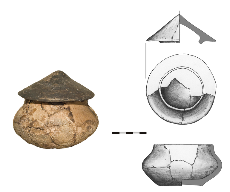 Waza typu W11 z pokrywką, niezdobiona. Krawędź zaokrąglona, dno niewyodrębnione. Domieszka tłuczonego kamienia i krzemienia. H – 6,2 cm, R1 – 9  cm, R3 – 12  cm, R4 – 6  cm. Pokrywka trójkątna w przekroju, średnica – 10,5 cm, wysokość – 4,5 cm