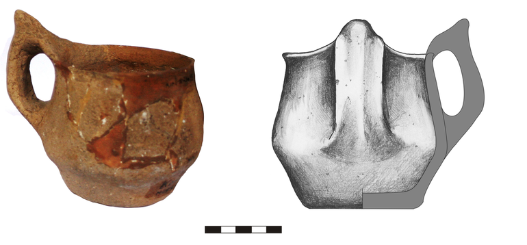 Kubek typu K21a, niezdobiony. Krawędź zaokrąglona, dno lekko wyodrębnione, ucho taśmowate typu ansa lunata. Domieszka tłuczonego kamienia i krzemienia. H – 10, 2 cm (bez ucha), 12,3  cm (z uchem), R1 – 10  cm, R2 – 9,5  cm, R3 – 11,5 cm, R4 – 7,5  cm