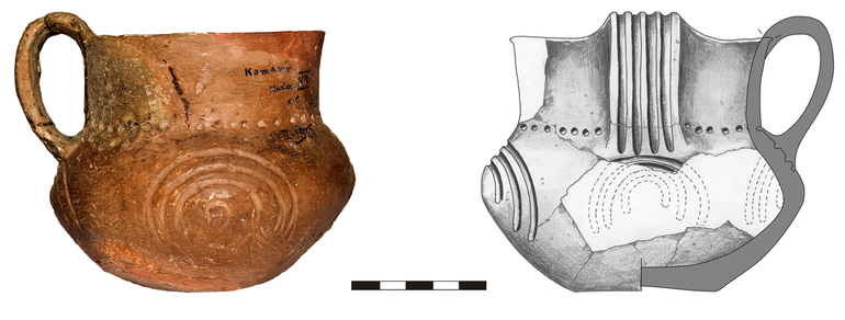 Kubek typu K22, zdobiony na uchu czterema pionowymi żłobkami, na brzuścu dookolnie okrągłymi nakłuciami, pod nimi czterema guzami plastycznymi, obwiedzionymi od góry trzema łukowatymi żłobkami. Krawędź ścięta prosto, dno niewyodrębnione. Domieszka tłuczonego kamienia i krzemienia. H – 10,5  cm, R1 – 10  cm, R2 – 9  cm, R3 – 12  cm, R4 – 5,5  cm