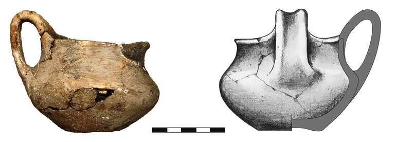 Kubek typu K22, niezdobiony. Krawędź zaokrąglona, dno wyodrębnione, ucho typu ansa lunata. Domieszka tłuczonego kamienia i krzemienia. H – 6,5 cm (bez ucha), 8,5 cm (z uchem), R1 – 7,8 cm, R2 – 7,3 cm, R3 – 9,6 cm, R4 – 4,5 cm
