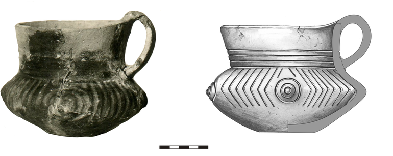 Dzban typu D21, zdobiony na szyjce poziomymi liniami rytymi, na brzuścu – czterema guzami plastycznymi obwiedzionymi trzema współśrodkowymi rytymi okręgami, pomiędzy którymi występują pionowe linie ryte. Krawędź zaokrąglona, dno niewyodrębnione. H – 11,5 cm (bez ucha), 12,8 cm (z uchem), R1 – 12,5 cm, R2 – 11,5 cm, R3 – 16,8 cm, R4 – 5,5 cm    (fot. Sulimirski 1968, Plate 18: 1)